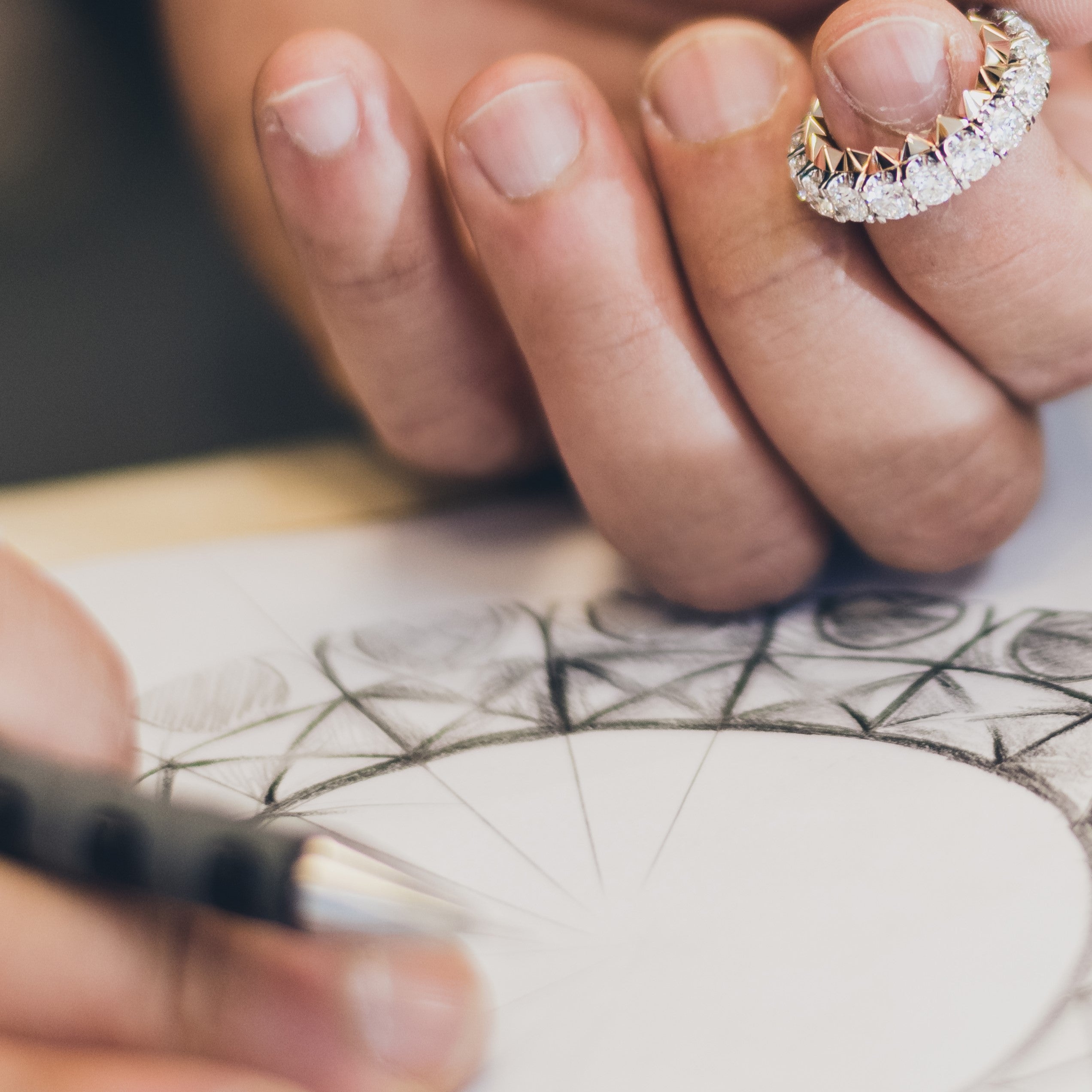 Tariq Riaz sketching ring design while holding prototype—engineer-designer merging precision and artistry in fine jewellery creation